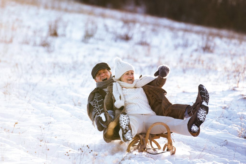 old couple sledding in snow