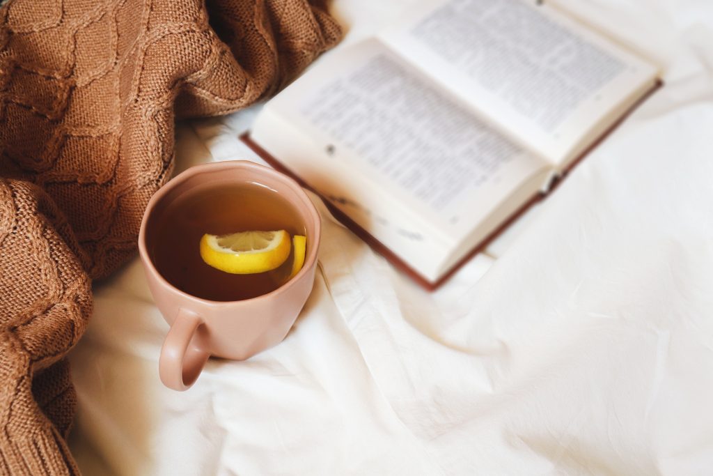 Cup of tea, cozy blanket, and book creating a relaxing self-care moment